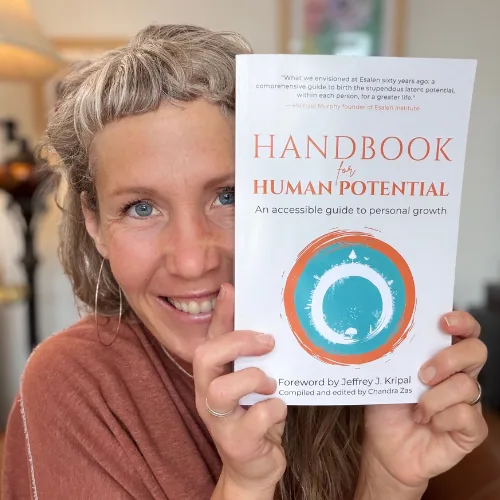 Chandra Zas, compiler and editor of Handbook for Human Potential, holding the book